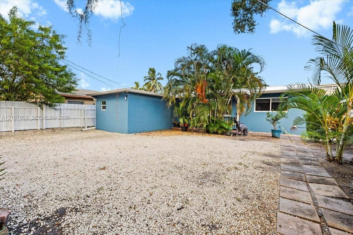 924 SW 15th Terrace, Fort Lauderdale, FL 33312 Spacious backyard featuring a gravel surface, concrete paver walkway, privacy fencing, and mature palm landscaping