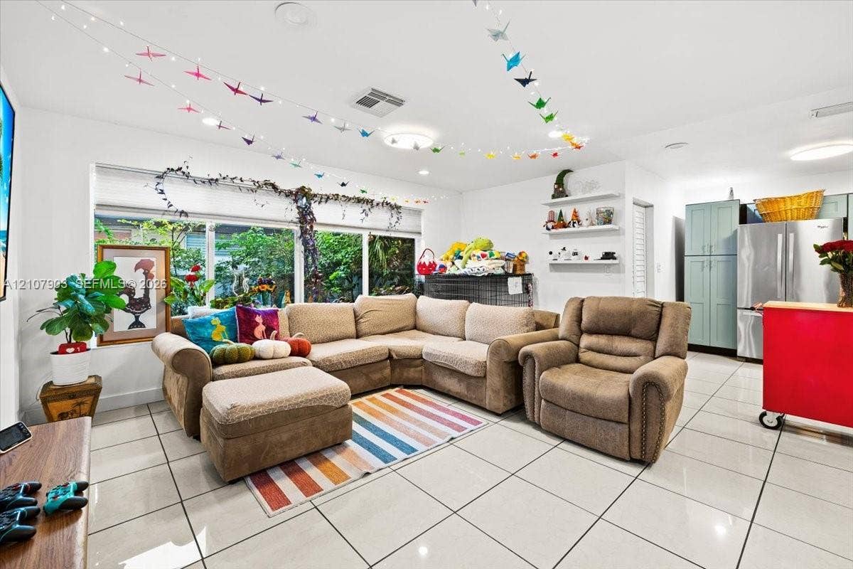 924 SW 15th Terrace, Fort Lauderdale, FL 33312 Large-format tile flooring, expansive window system, built-in wall shelving, and tall shaker-style cabinetry with stainless steel refrigerator
