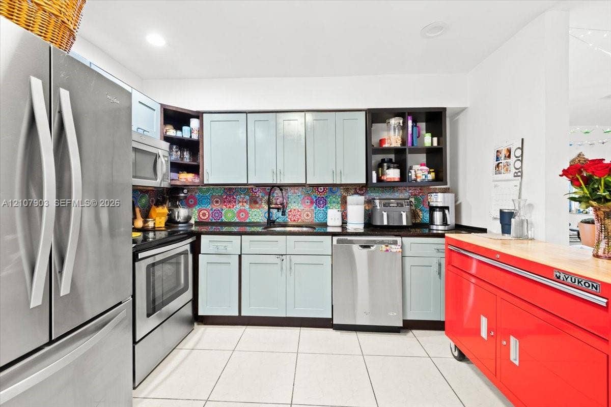 924 SW 15th Terrace, Fort Lauderdale, FL 33312 Kitchen featuring light blue cabinetry, patterned tile backsplash, stainless steel appliances, dark stone-finish countertops, and tile flooring