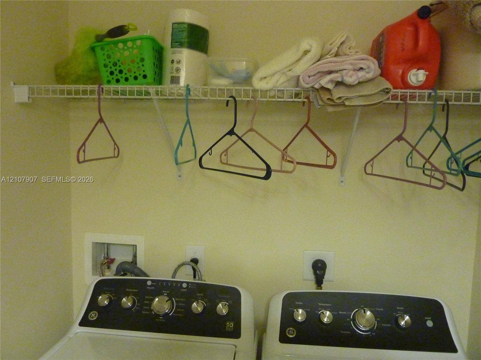 Laundry area featuring a wall-mounted wire storage shelf and recessed water supply connections