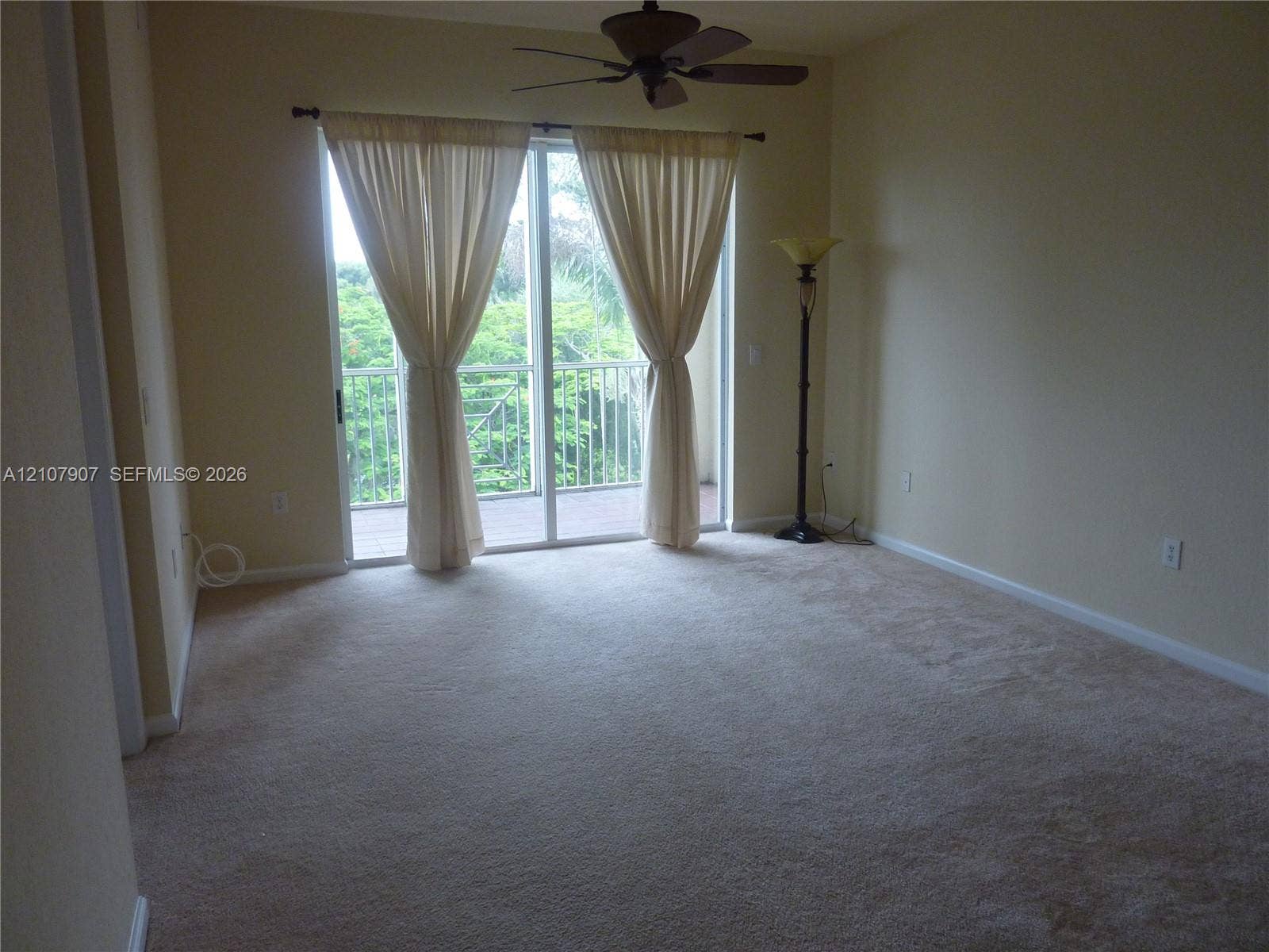 Carpeted room featuring a ceiling fan and sliding glass doors with balcony access