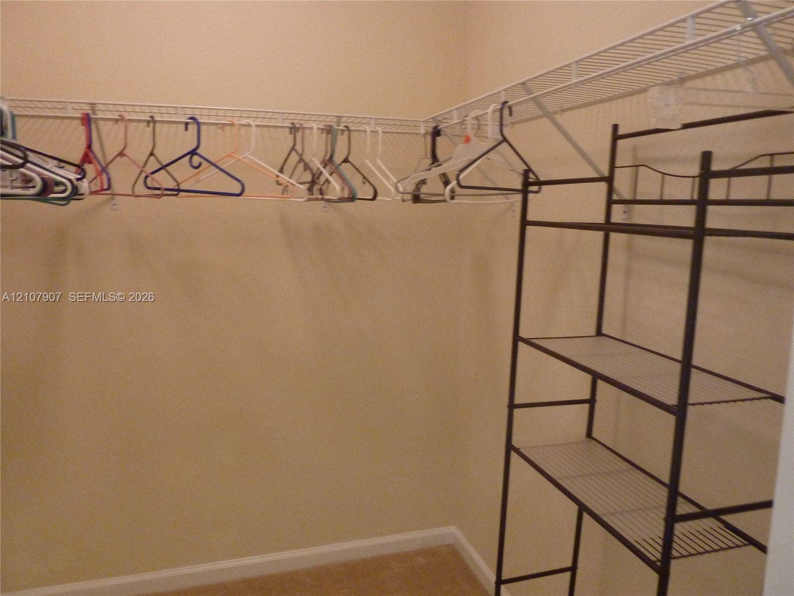 Walk-in closet featuring wall-to-wall wire shelving and a freestanding dark metal storage rack