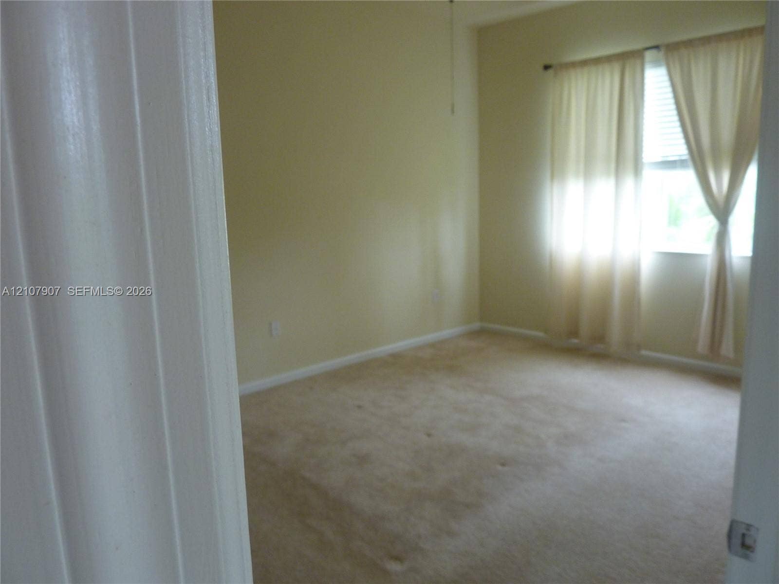 Interior room featuring carpeting, high ceilings, and a window with blinds