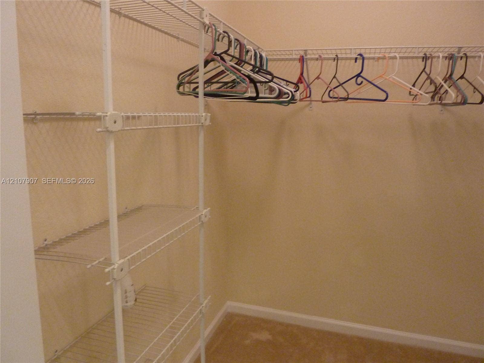 Walk-in closet featuring white wire shelving units and integrated clothing rods