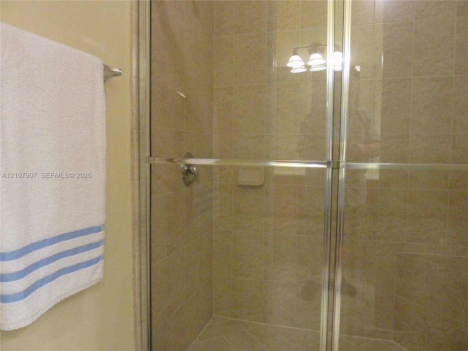 Shower enclosure featuring neutral-toned wall tile, a metal-framed glass door, and integrated tile soap niche