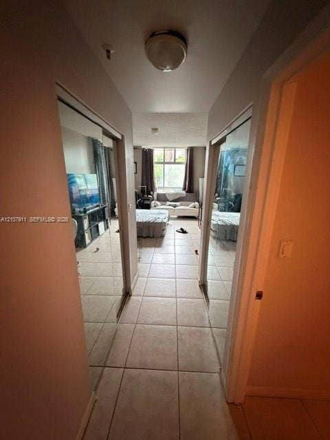 9755 NW 52nd Street, #218, Doral, FL 33178 Hallway featuring light-toned tile flooring and dual mirrored sliding-door closets
