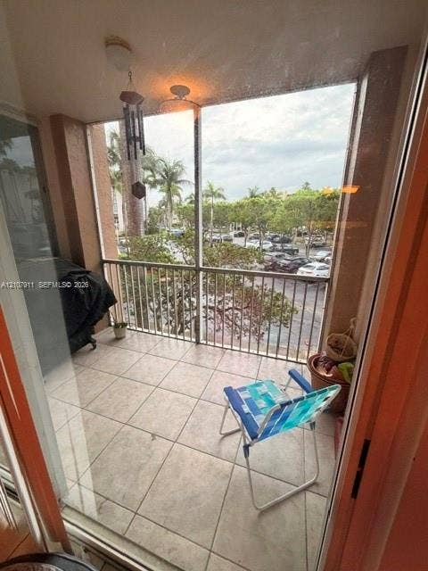 9755 NW 52nd Street, #218, Doral, FL 33178 Screened-in balcony featuring large-format tile flooring, metal railing, and a ceiling-mounted light fixture