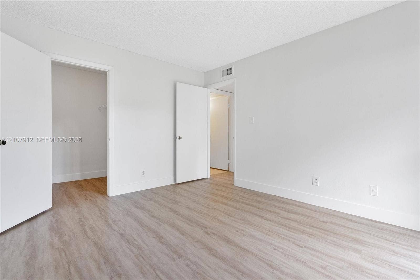 Neutral-toned walls, wood-finish flooring, and multiple interior doors