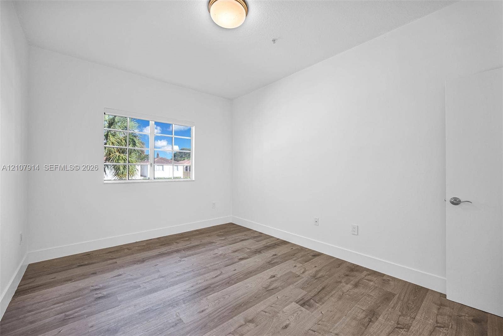 7340 NW 114th Avenue, #205, Doral, FL 33178 Room featuring wood-finish flooring, a multi-pane window, and a flush-mount ceiling fixture