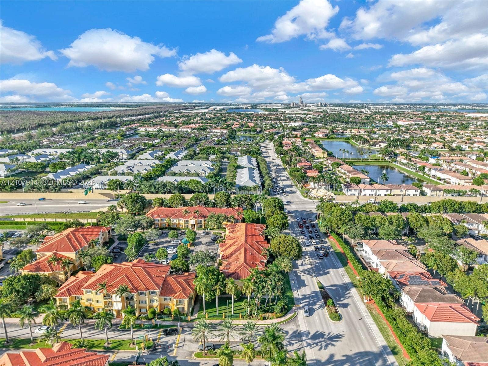 7340 NW 114th Avenue, #205, Doral, FL 33178 Aerial perspective of a multi-building residential complex featuring Mediterranean-style architecture, terracotta-tiled roofs, manicured palm landscaping, and integrated surface parking