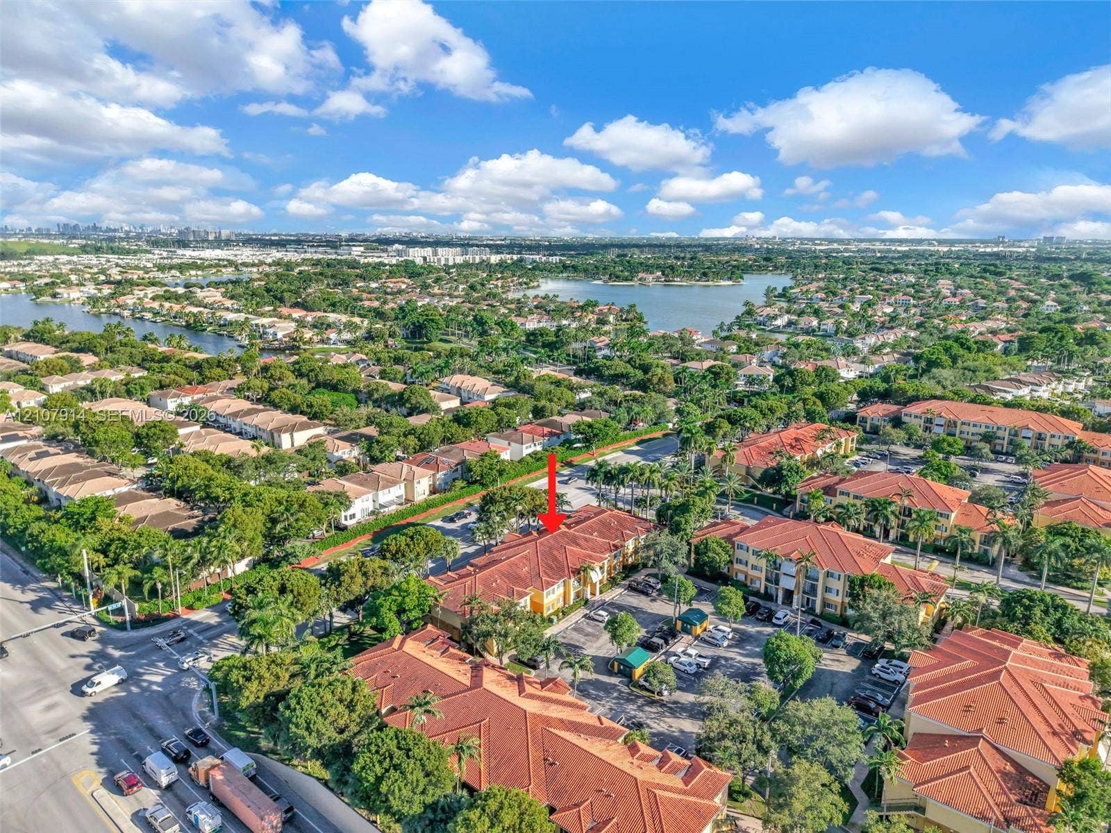 7340 NW 114th Avenue, #205, Doral, FL 33178 Aerial perspective featuring a multi-story residential building with a terracotta-style tiled roof, stucco exterior, and dedicated surface parking
