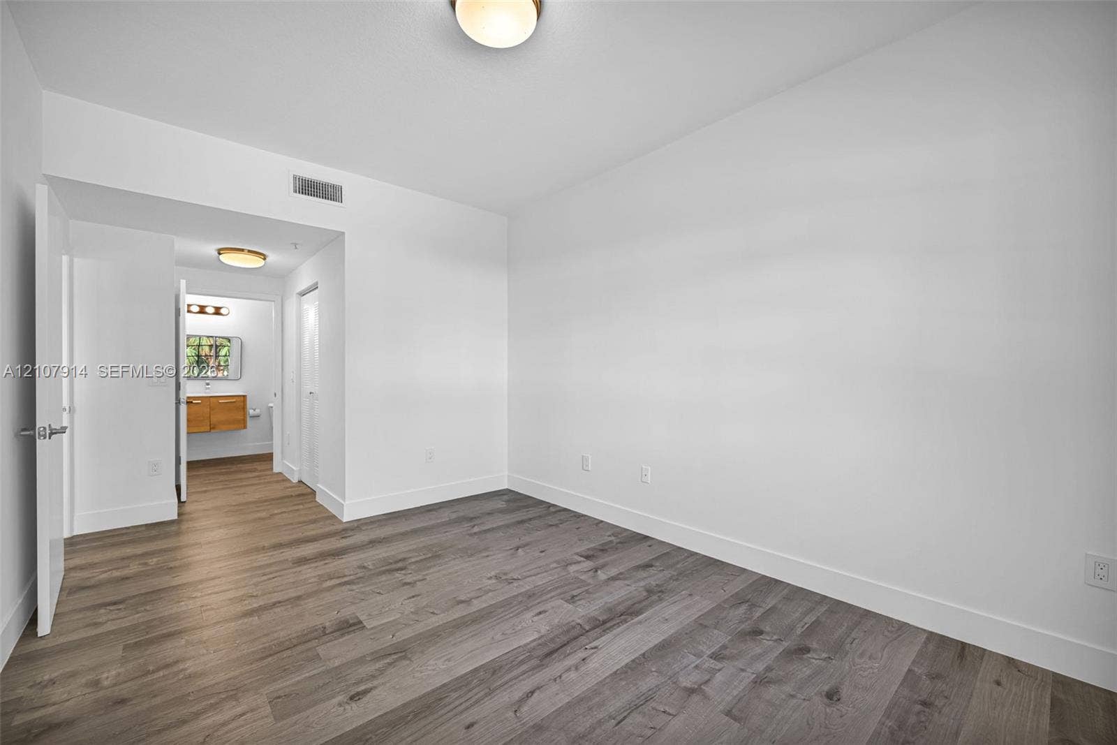 7340 NW 114th Avenue, #205, Doral, FL 33178 Neutral-toned interior space featuring wood-finish flooring, crisp white walls, and flush-mount ceiling light fixtures