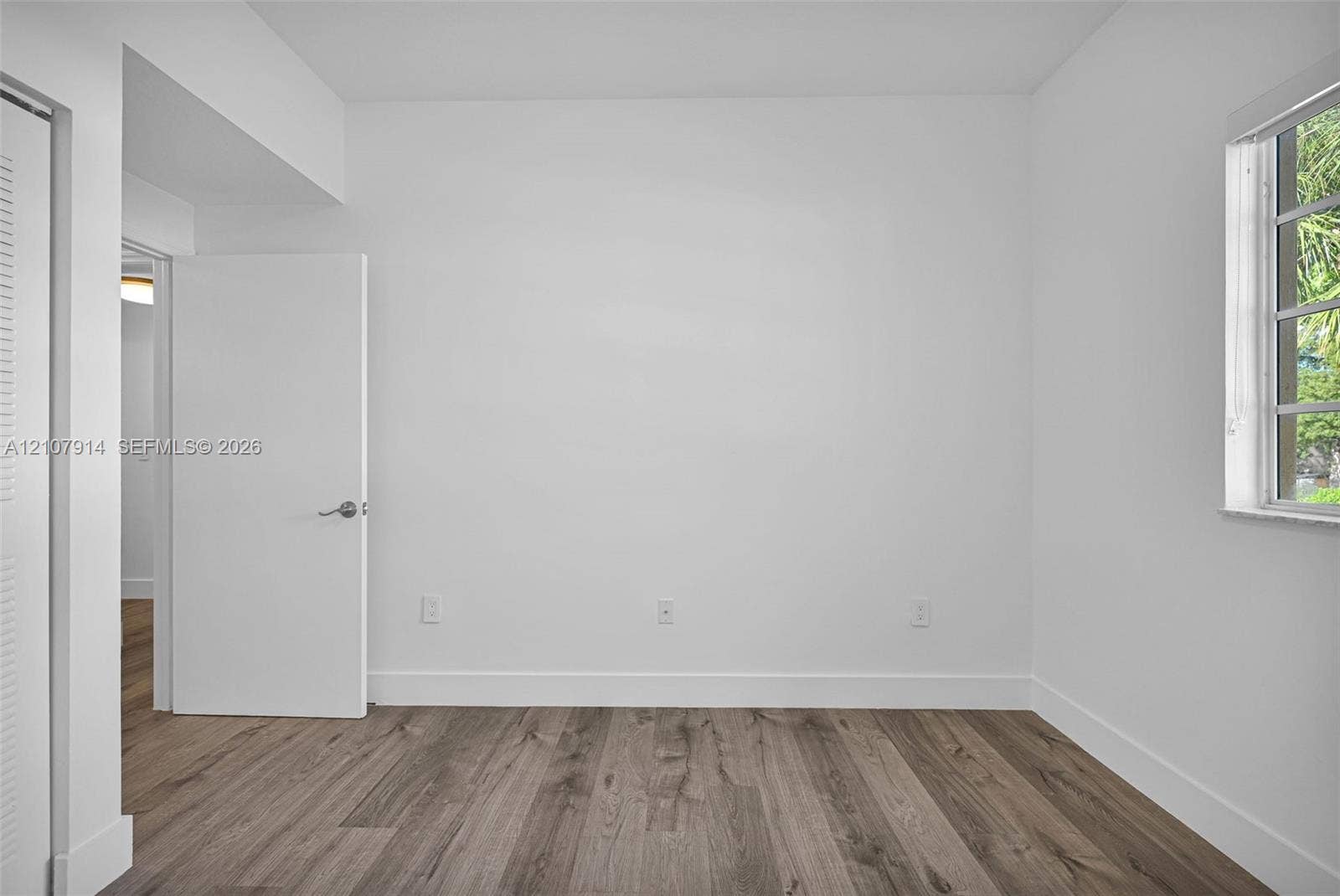 7340 NW 114th Avenue, #205, Doral, FL 33178 Interior space featuring wood-finish flooring, a multi-pane window, and white interior doors with brushed nickel hardware