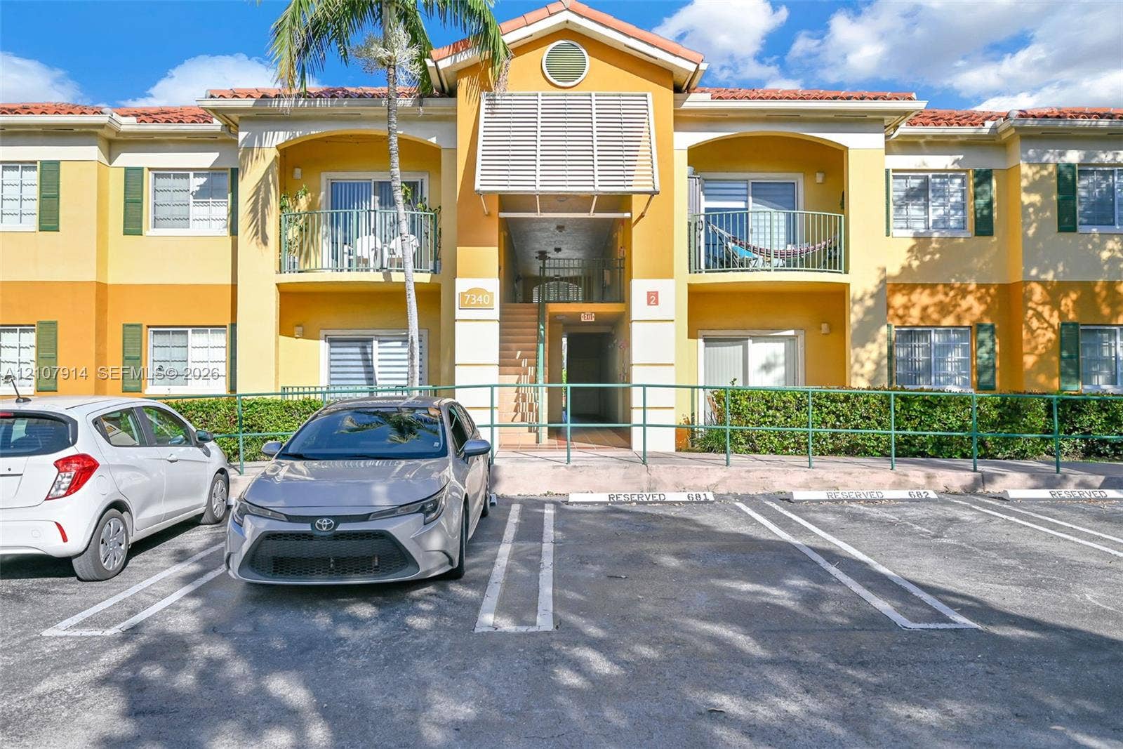 7340 NW 114th Avenue, #205, Doral, FL 33178 Exterior facade featuring a tile roof, stucco finish, shuttered windows, and private balconies with metal railings