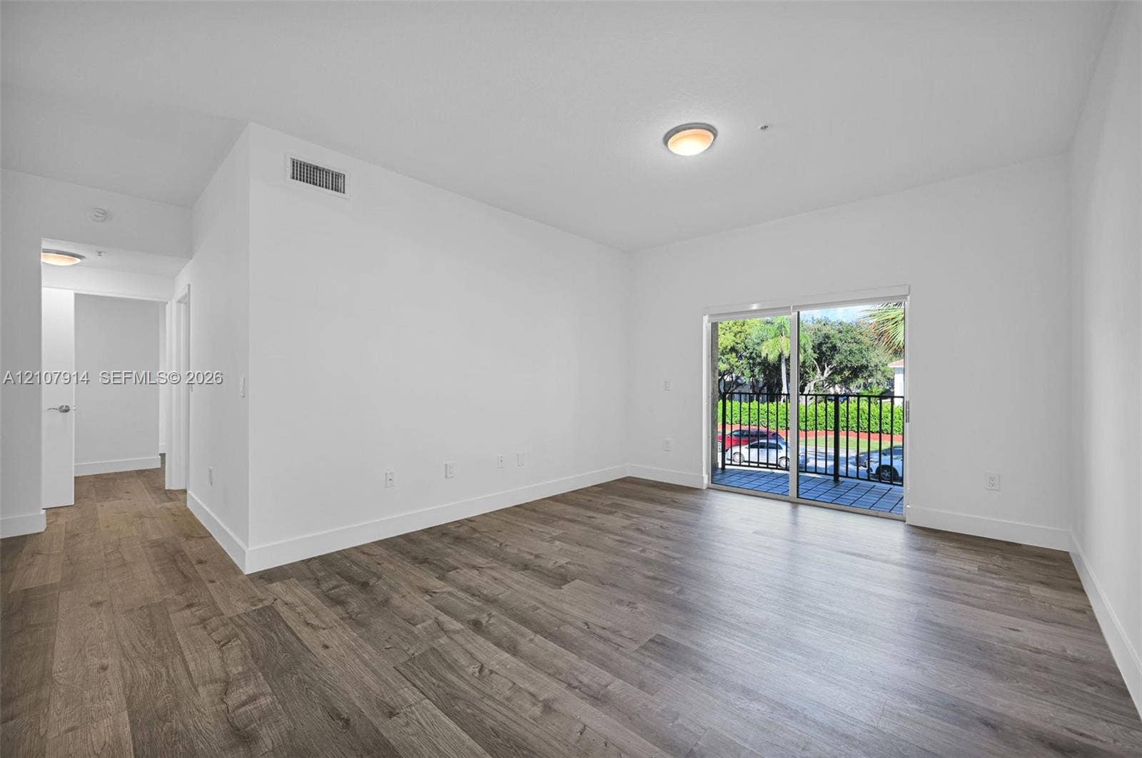 7340 NW 114th Avenue, #205, Doral, FL 33178 Open-concept room featuring wood-finish flooring, sliding glass doors, and a private balcony with metal railing