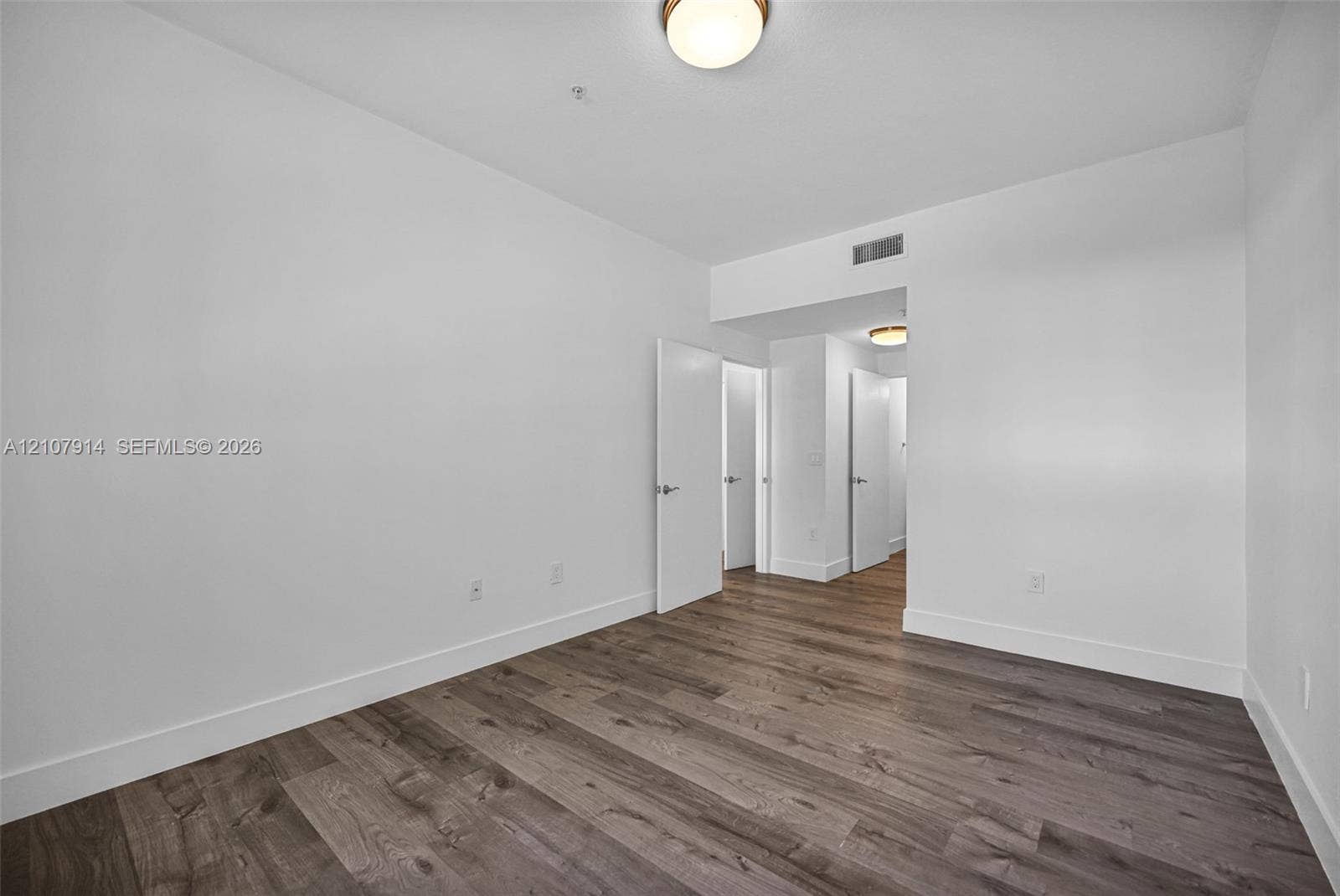 7340 NW 114th Avenue, #205, Doral, FL 33178 Room interior featuring wood-finish flooring, crisp white walls, and flush-mount lighting fixtures