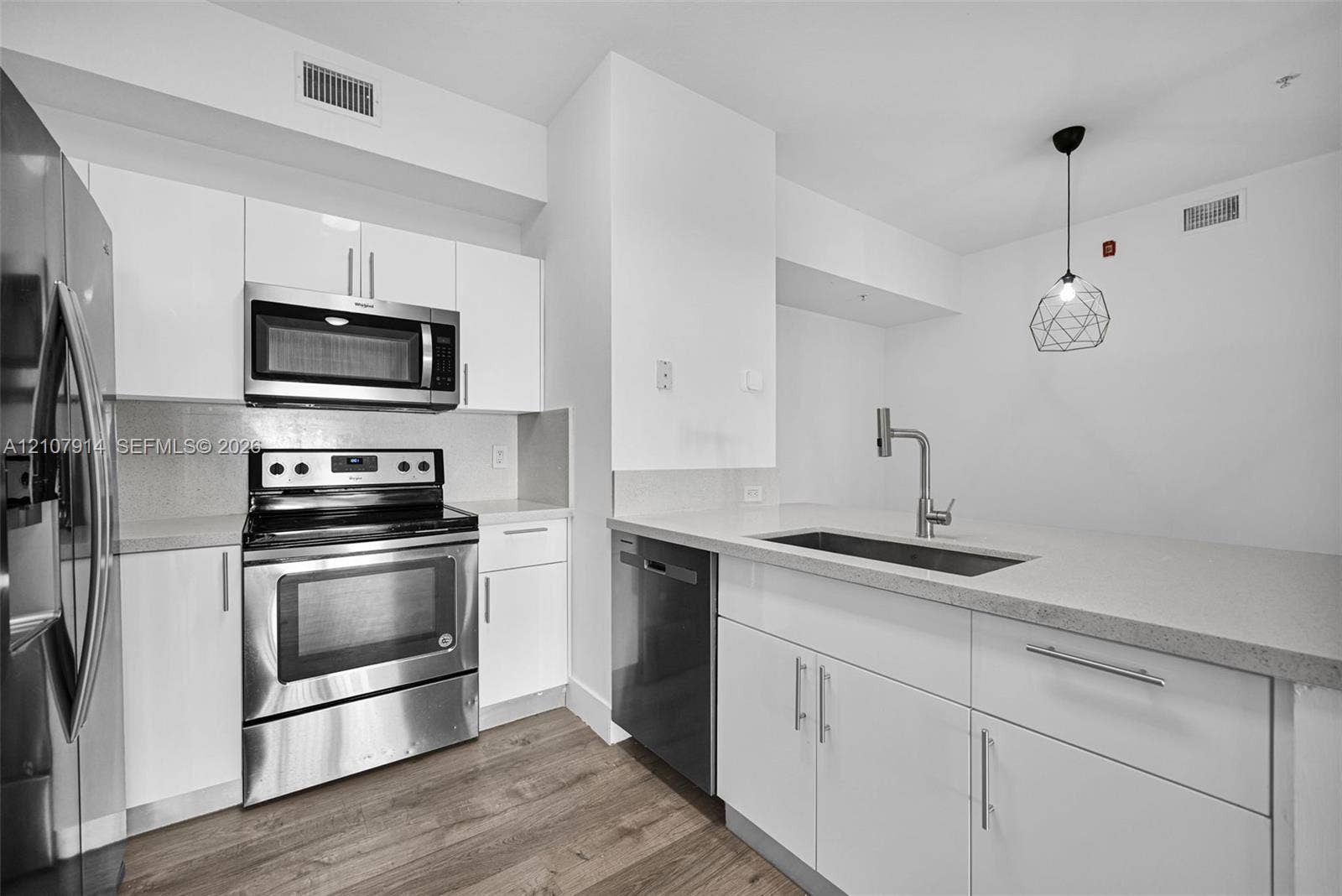 7340 NW 114th Avenue, #205, Doral, FL 33178 Kitchen featuring white cabinetry, solid surface countertops, stainless steel appliances, a single-basin undermount sink with a high-arch faucet, and wood-finish flooring