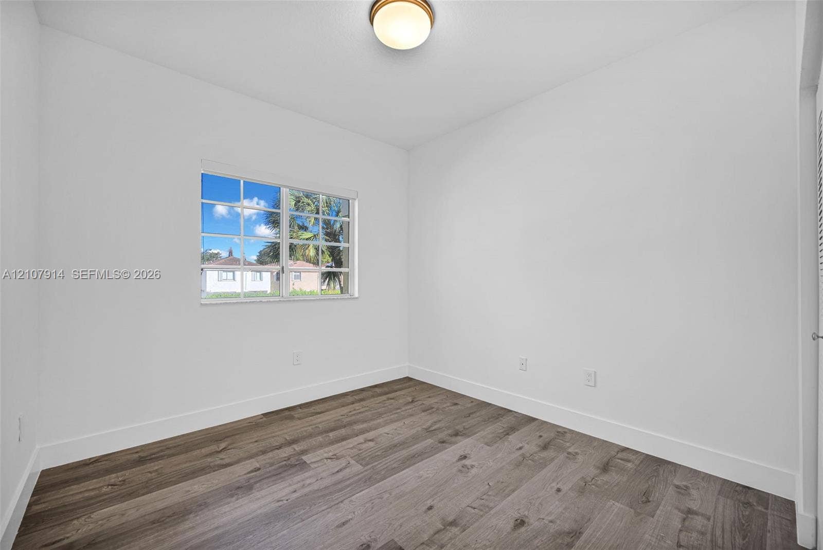 7340 NW 114th Avenue, #205, Doral, FL 33178 Interior room featuring wood-finish flooring, a multi-pane window, and a central flush-mount ceiling fixture