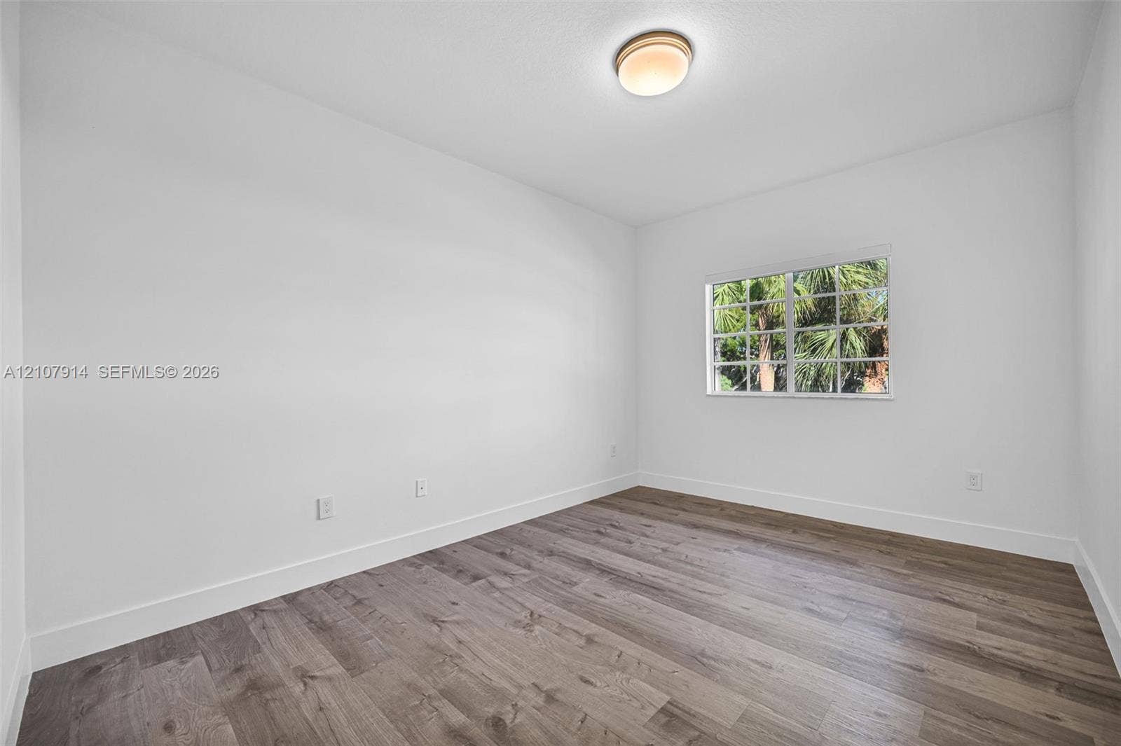 7340 NW 114th Avenue, #205, Doral, FL 33178 Neutral-toned room featuring wood-finish flooring, a multi-pane window, and a flush-mount dome light fixture