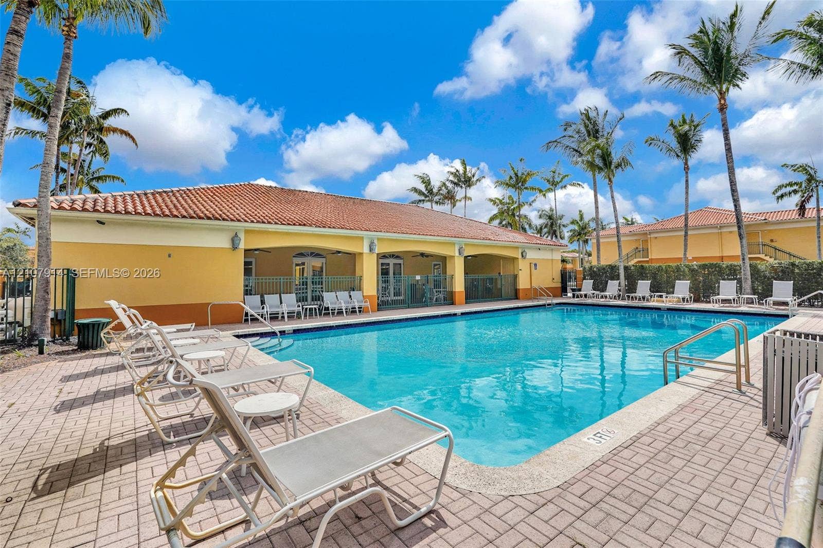 7340 NW 114th Avenue, #205, Doral, FL 33178 In-ground swimming pool featuring a concrete deck and a covered pavilion with arched entryways and a tile roof