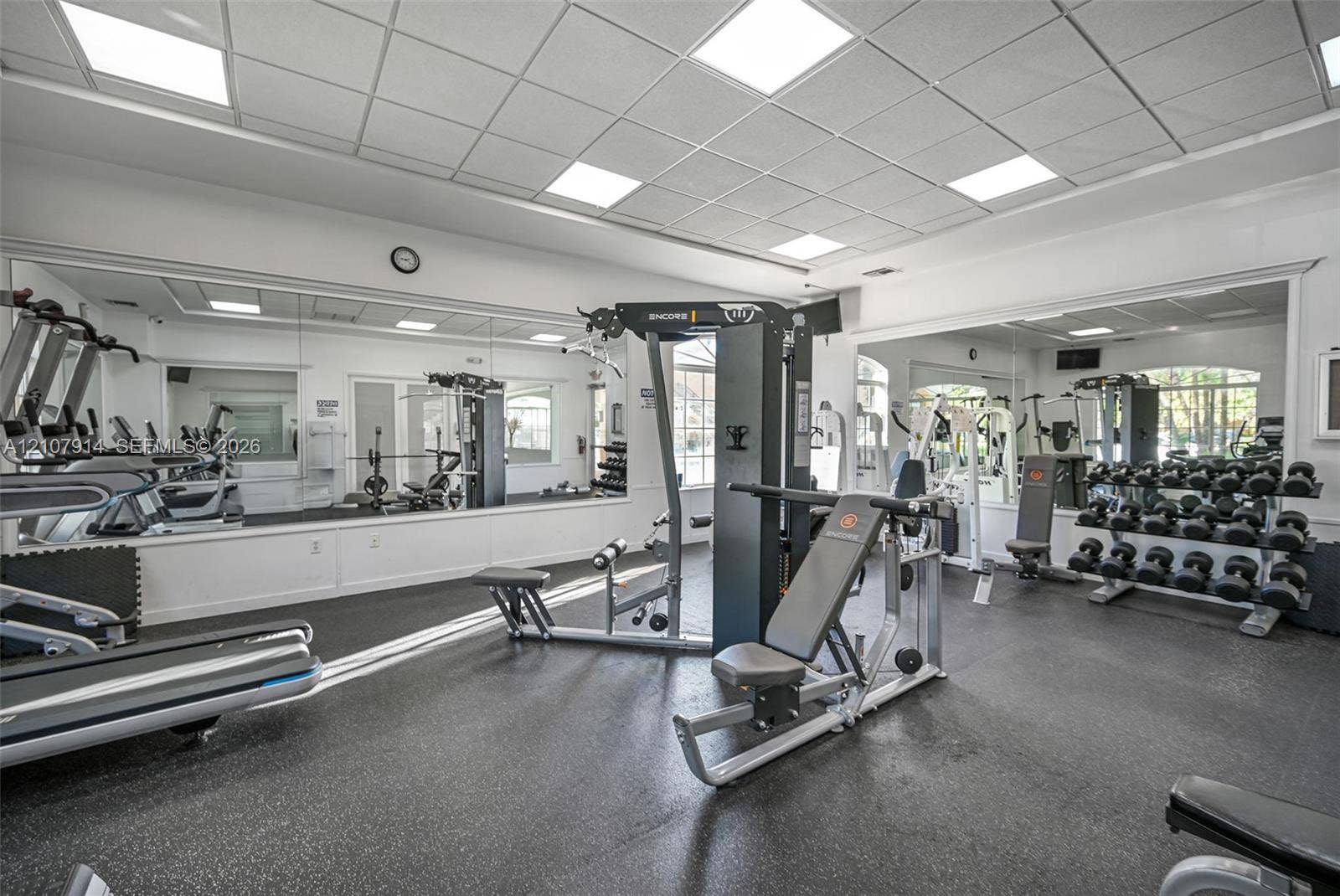 7340 NW 114th Avenue, #205, Doral, FL 33178 Fitness center featuring wall-to-wall mirrors, recessed grid ceiling lighting, and durable rubberized flooring