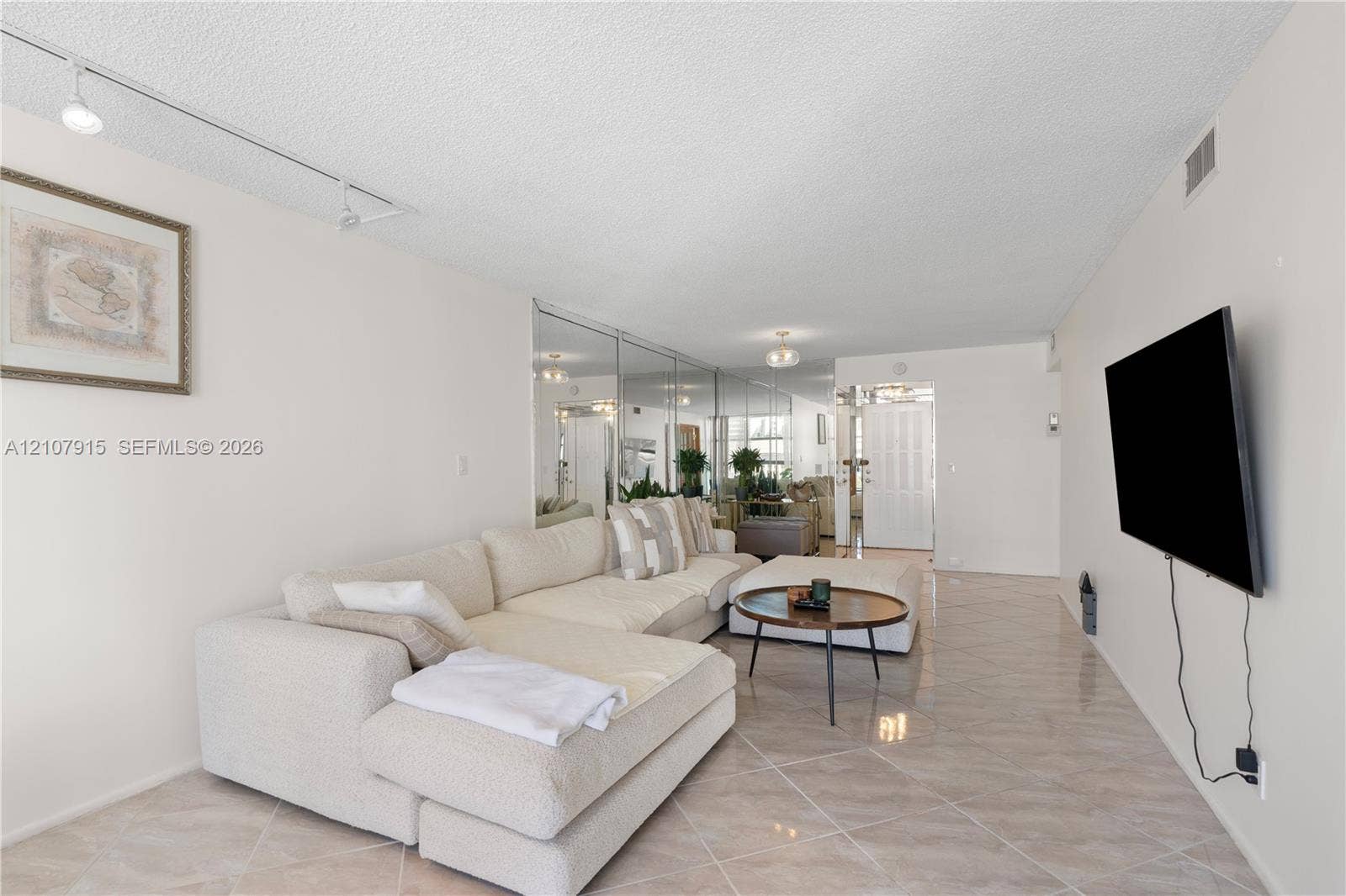 400 Leslie Drive, #622, Hallandale Beach, Hallandale Beach, FL 33009 Neutral-toned interior space featuring diagonal-patterned ceramic tile flooring, full-wall mirrored paneling, and adjustable track lighting