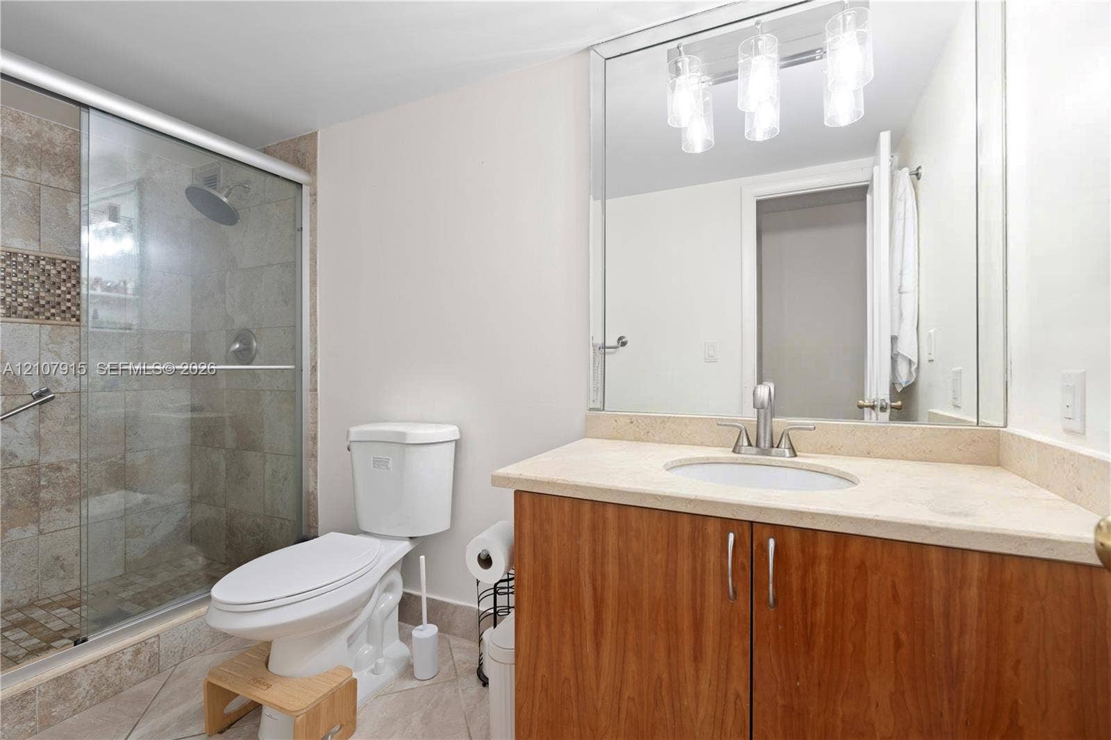 400 Leslie Drive, #622, Hallandale Beach, Hallandale Beach, FL 33009 Vanity featuring a light-toned stone countertop, wood-finish cabinetry, a large wall-mounted mirror, and a three-bulb light fixture