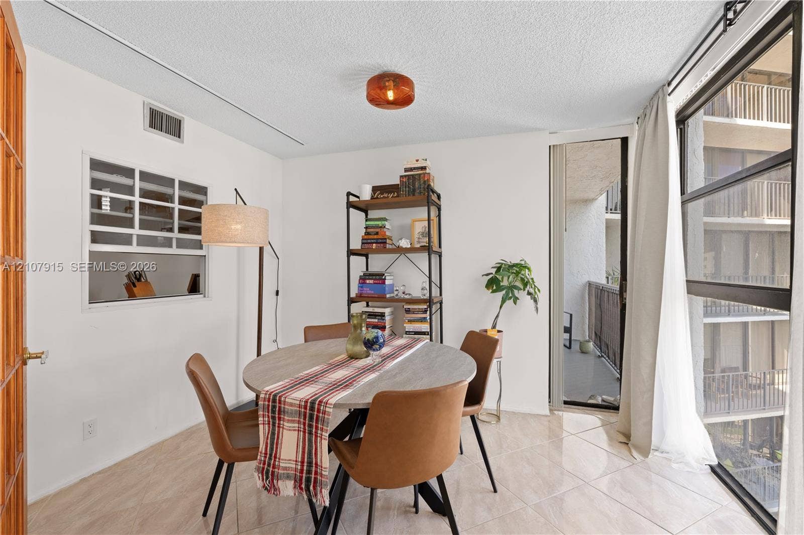 400 Leslie Drive, #622, Hallandale Beach, Hallandale Beach, FL 33009 Dining area featuring large-format ceramic tile flooring, a built-in kitchen pass-through window, and floor-to-ceiling windows with sliding door access to a private balcony