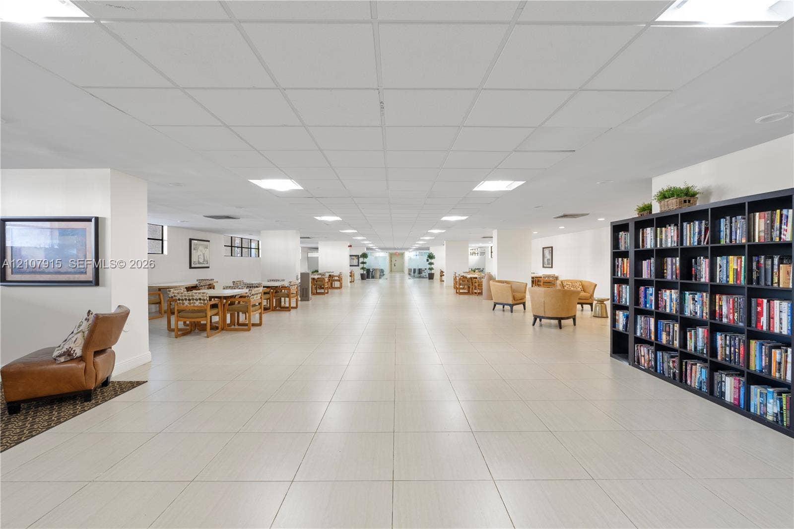 400 Leslie Drive, #622, Hallandale Beach, Hallandale Beach, FL 33009 Expansive common area featuring large-format tile flooring, a suspended grid ceiling with recessed panel lighting, and a floor-to-ceiling built-in bookcase