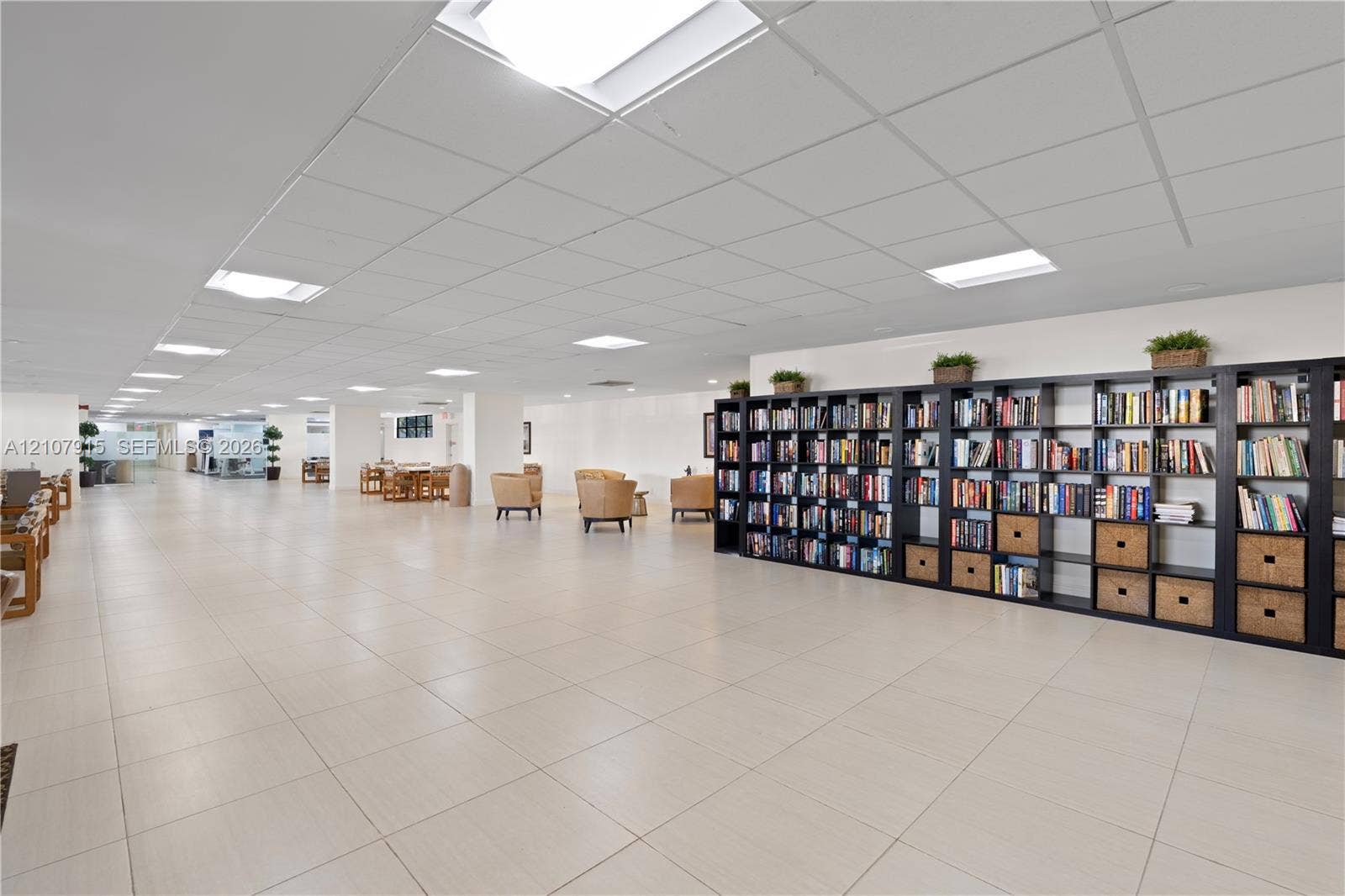 400 Leslie Drive, #622, Hallandale Beach, Hallandale Beach, FL 33009 Expansive open-concept space featuring large-format tile flooring, recessed grid ceiling, integrated square lighting panels, and extensive floor-to-ceiling built-in shelving