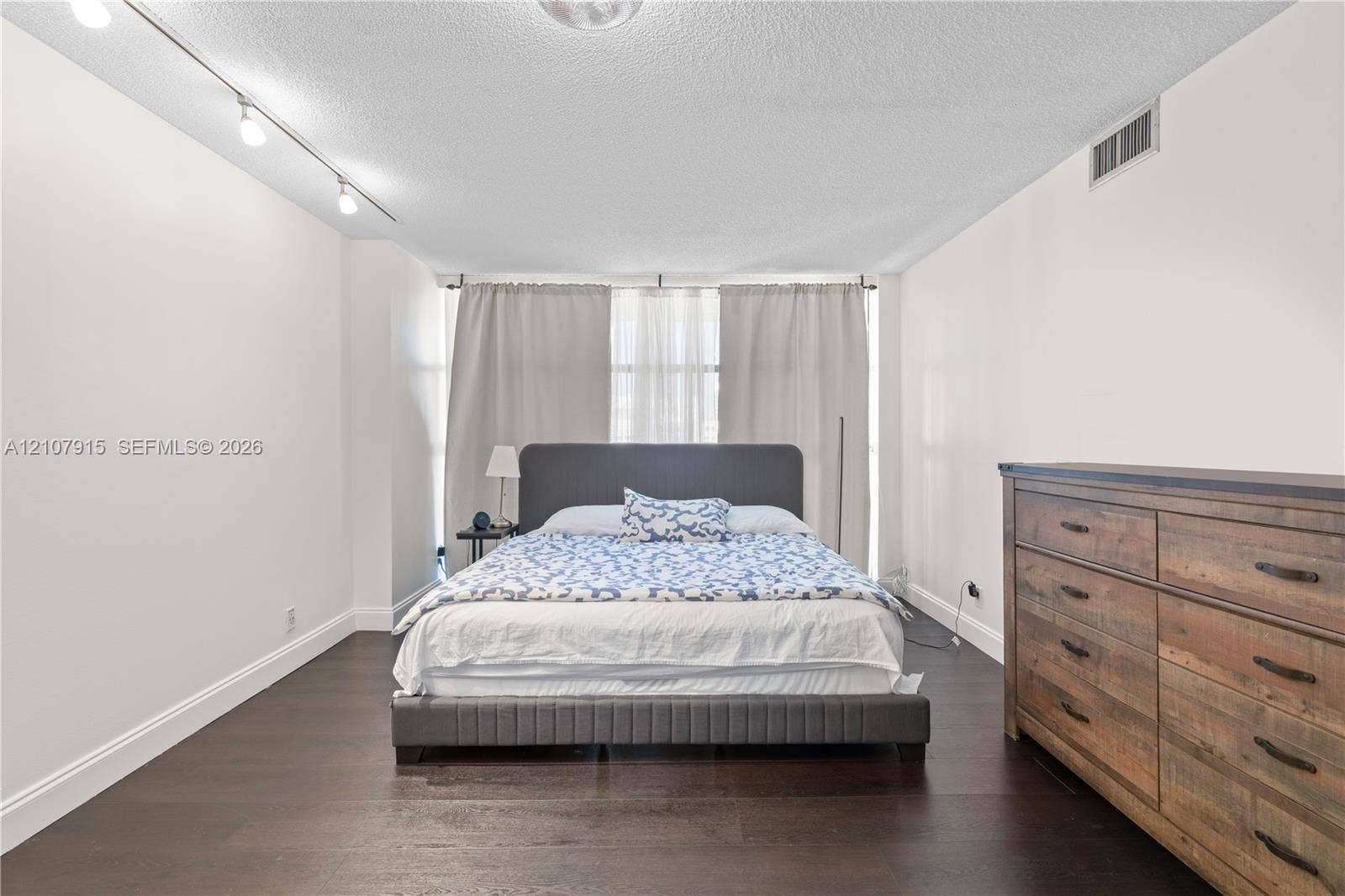 400 Leslie Drive, #622, Hallandale Beach, Hallandale Beach, FL 33009 Spacious interior featuring dark wood-finish flooring, adjustable track lighting, and expansive window coverage with full-length drapery