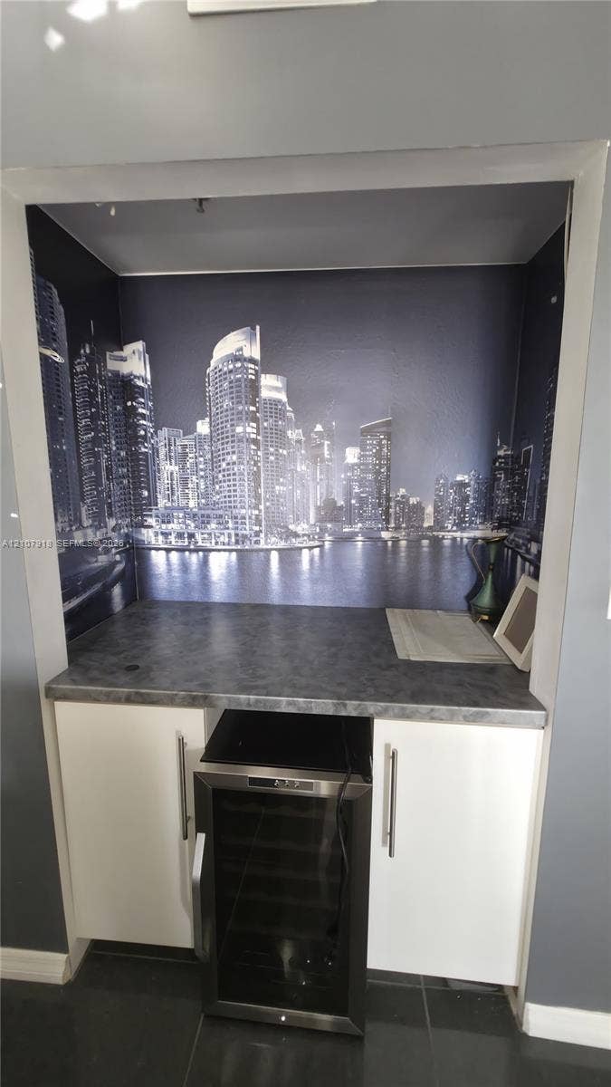 Built-in wet bar featuring white cabinetry, stone-finish countertop, and under-counter beverage refrigerator