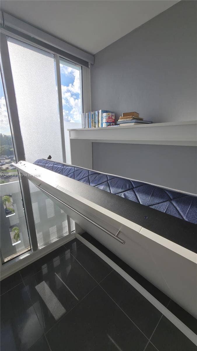 Built-in wall unit with integrated shelving, floor-to-ceiling glass window, and dark tile flooring