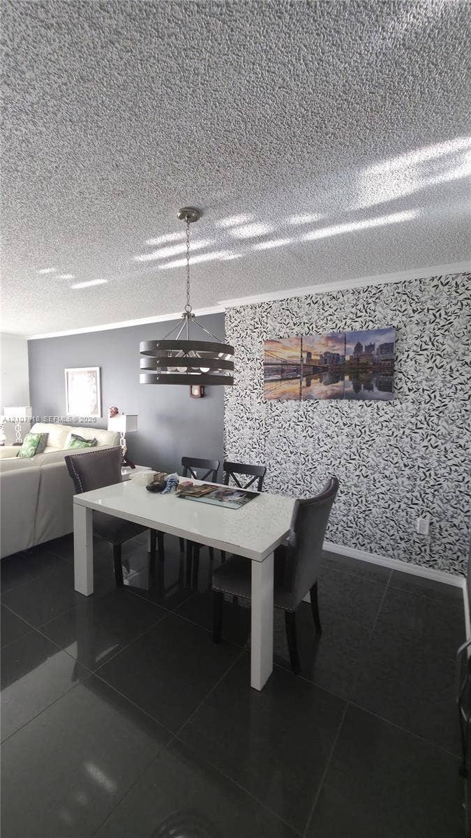 Large-format tile flooring, textured ceiling, decorative patterned wall covering, and a multi-tier pendant light fixture