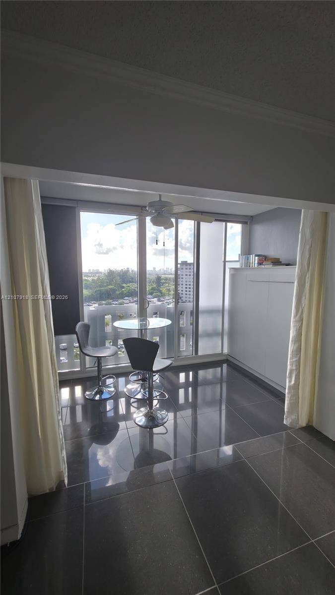 Floor-to-ceiling sliding glass doors, large-format polished tile flooring, white built-in cabinetry, and ceiling-mounted fan