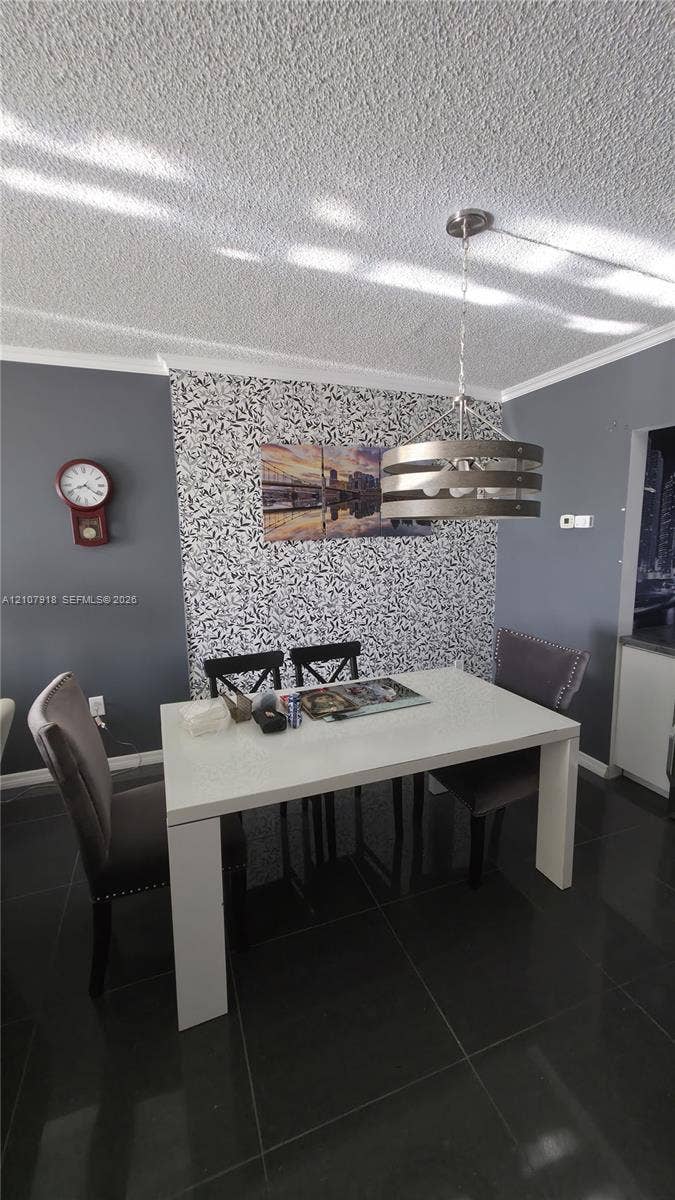 Textured ceiling, accent wall with patterned finish, and industrial-style metal drum pendant light over large-format tile flooring