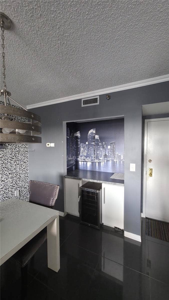 Built-in wet bar featuring dark cabinetry, countertop, and integrated wine cooler, complemented by high-gloss floor tile and a contemporary multi-tier drum pendant light