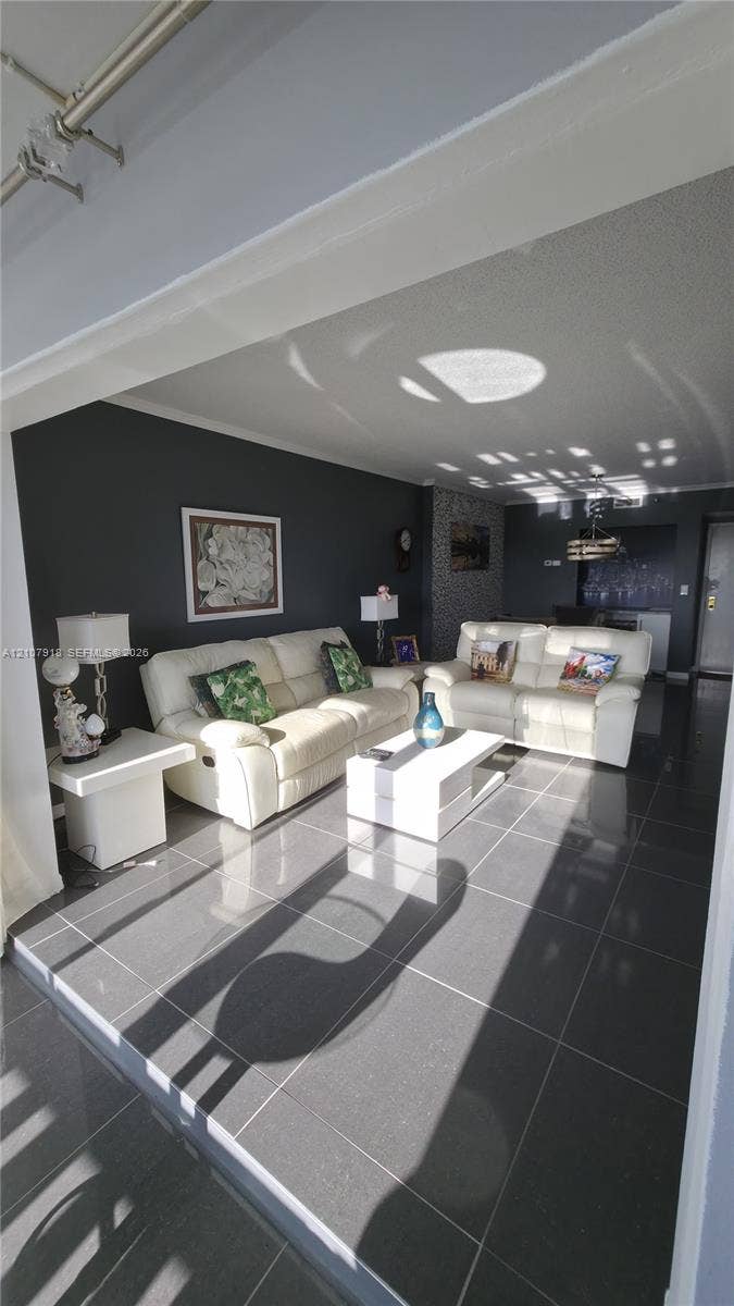 Large-format tile flooring, textured ceiling, and a prominent feature wall with masonry accents