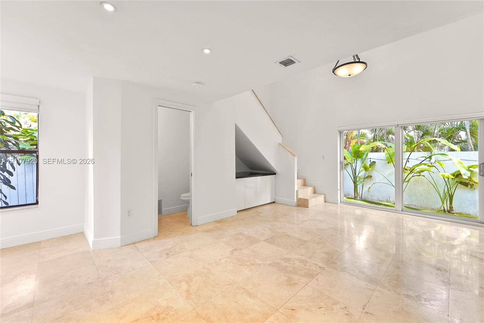 3062 Shipping Avenue, #3062, Miami, Miami, FL 33133 Interior space featuring large-format tile flooring, sliding glass doors, recessed lighting, and built-in cabinetry beneath an integrated staircase