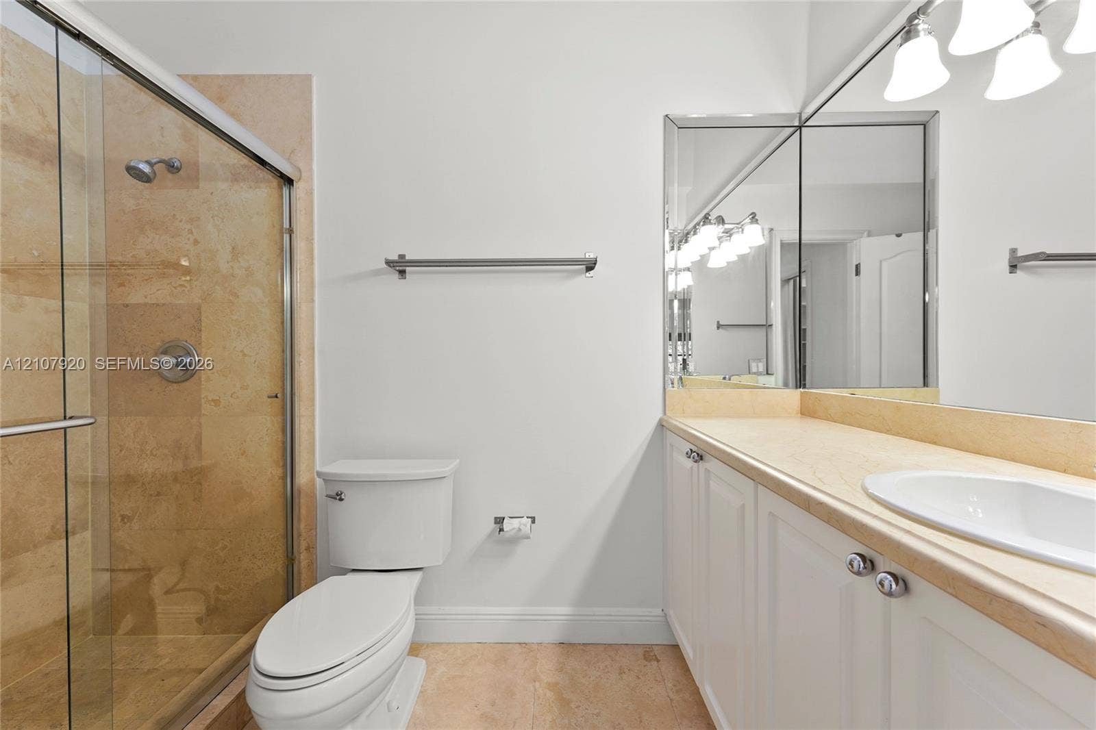 3062 Shipping Avenue, #3062, Miami, Miami, FL 33133 Walk-in shower with stone tile surround, vanity with stone countertop, integrated undermount sink, expansive vanity mirror, and polished metal fixtures