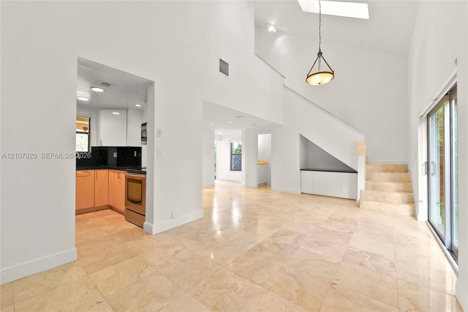 3062 Shipping Avenue, #3062, Miami, Miami, FL 33133 Open-concept living space featuring high vaulted ceilings, large skylight, natural stone flooring, custom built-in cabinetry, and sliding glass doors