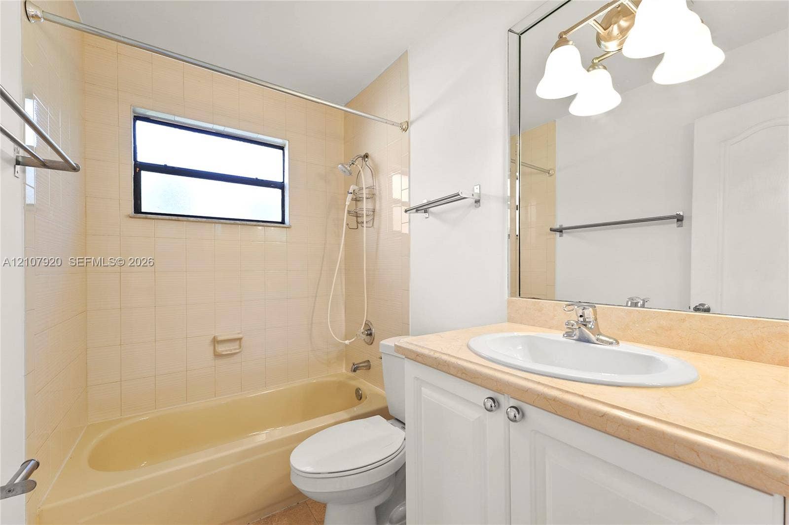 3062 Shipping Avenue, #3062, Miami, Miami, FL 33133 Bathroom featuring a neutral-toned tile shower surround, a built-in tub, a white vanity with a light-colored countertop, and a large-format mirror with integrated three-bulb lighting