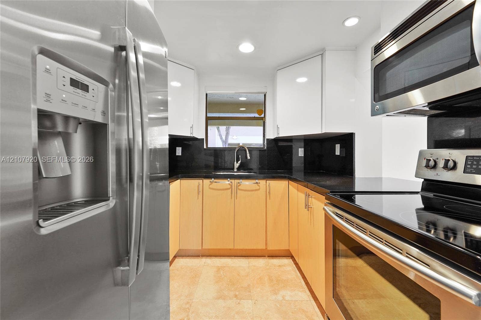 3062 Shipping Avenue, #3062, Miami, Miami, FL 33133 Kitchen featuring stainless steel appliances, dark stone countertops, high-gloss upper cabinetry, wood-finish lower cabinetry, and tile flooring