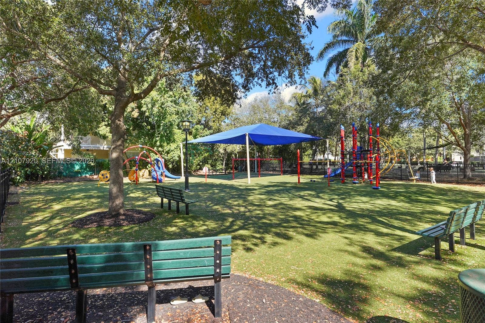 3062 Shipping Avenue, #3062, Miami, Miami, FL 33133 Recreational outdoor space featuring permanent playground structures, a large shade canopy, mature shade trees, and built-in metal bench seating