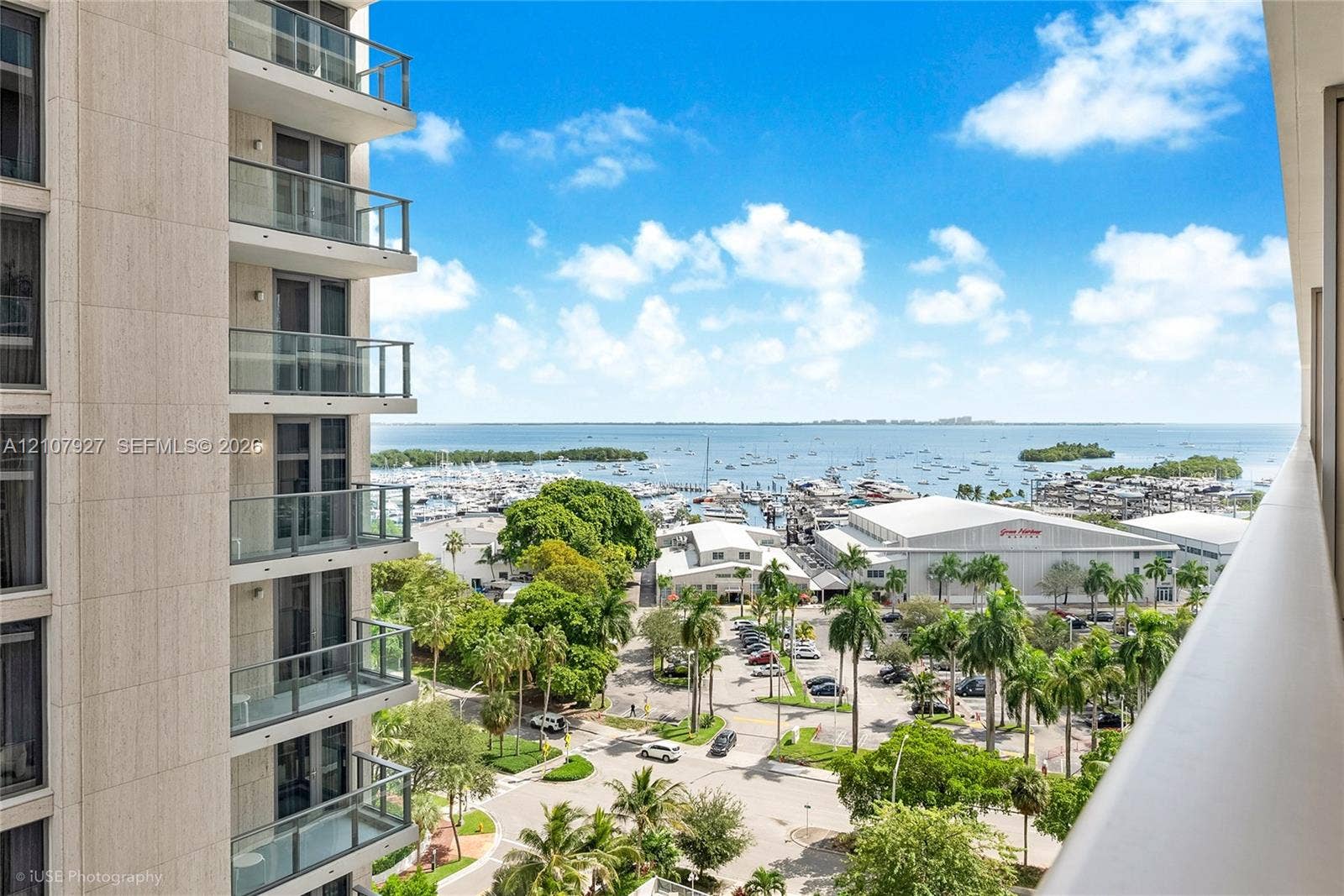 High-rise balcony featuring glass railings, floor-to-ceiling windows, and panoramic water and marina scenery