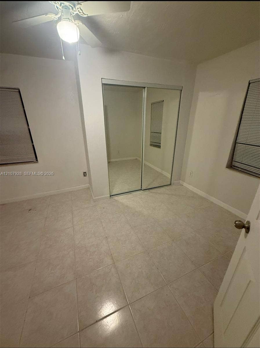 815 Foster Road, #2, Hallandale Beach, Hallandale Beach, FL 33009 Neutral tile flooring, sliding mirrored closet doors, dual windows with fitted blinds, and a central ceiling fan with an integrated light fixture