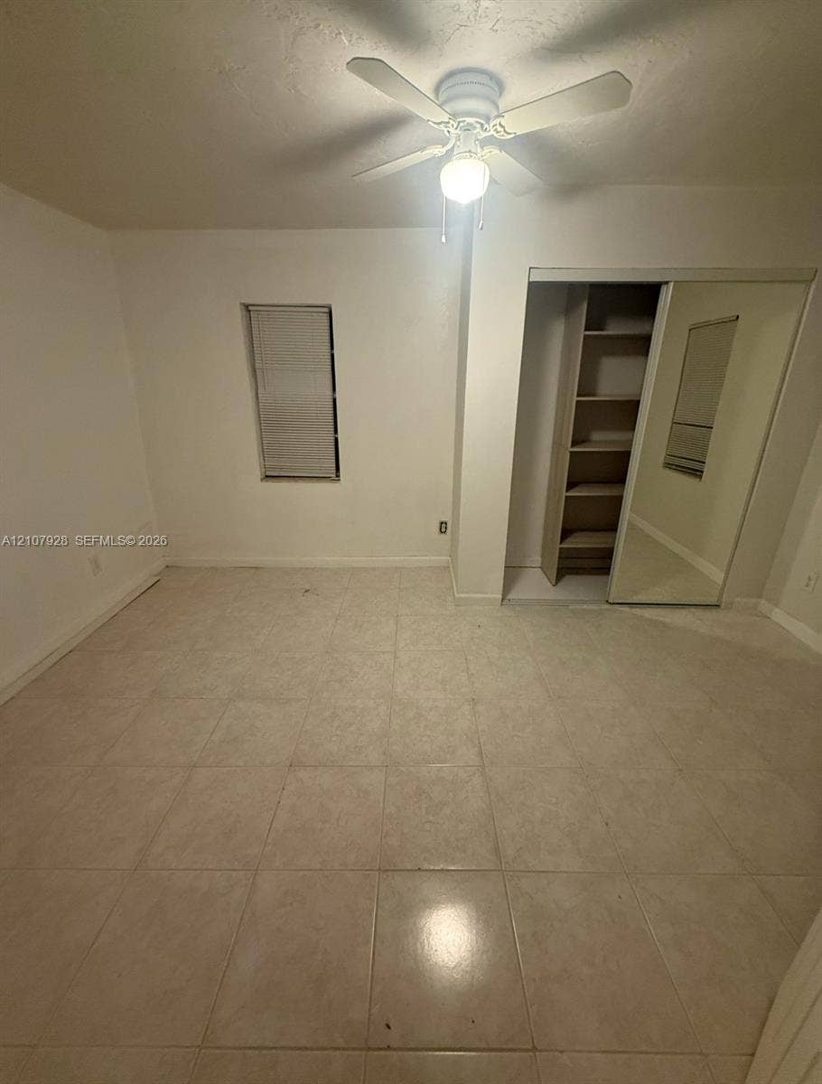 815 Foster Road, #2, Hallandale Beach, Hallandale Beach, FL 33009 Neutral tile flooring, ceiling fan with integrated lighting, recessed window, closet with built-in shelving, and mirrored sliding closet doors