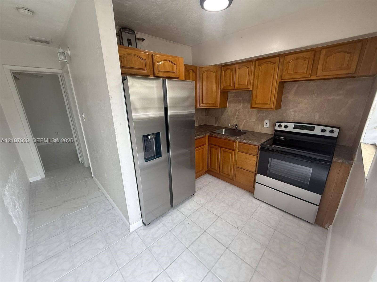 815 Foster Road, #2, Hallandale Beach, Hallandale Beach, FL 33009 Kitchen featuring wood cabinetry, stainless steel side-by-side refrigerator, stainless steel electric range, stone-patterned backsplash, and ceramic tile flooring