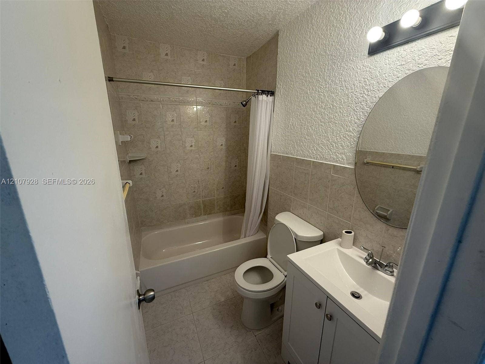 815 Foster Road, #2, Hallandale Beach, Hallandale Beach, FL 33009 Bathroom featuring a vanity with integrated sink, oval wall-mounted mirror, three-light fixture, tile wainscoting, and a tiled tub and shower combination