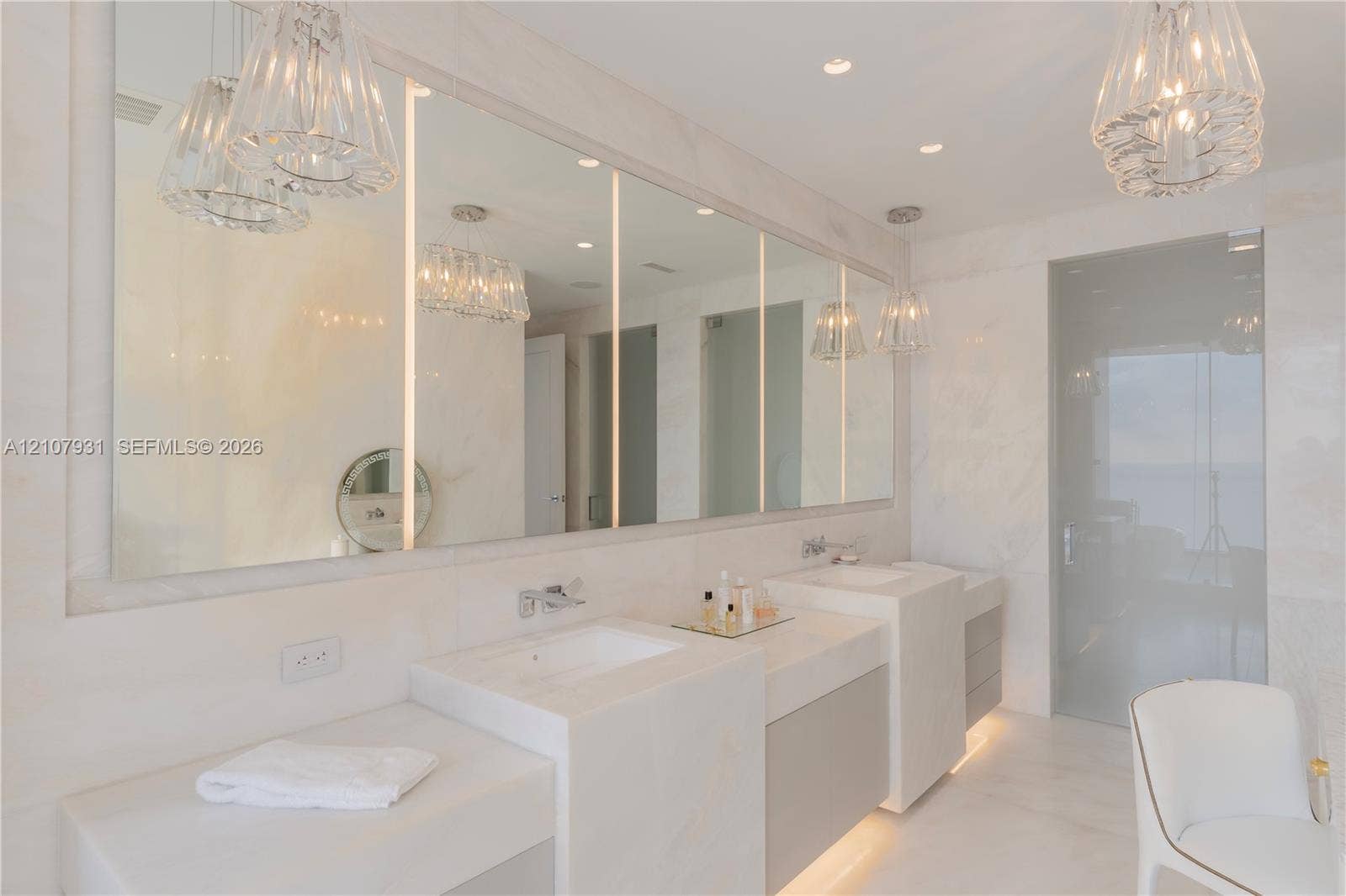 Double vanity featuring integrated rectangular sinks, stone countertops, full-width mirror with vertical LED lighting, recessed ceiling lighting, and pendant fixtures